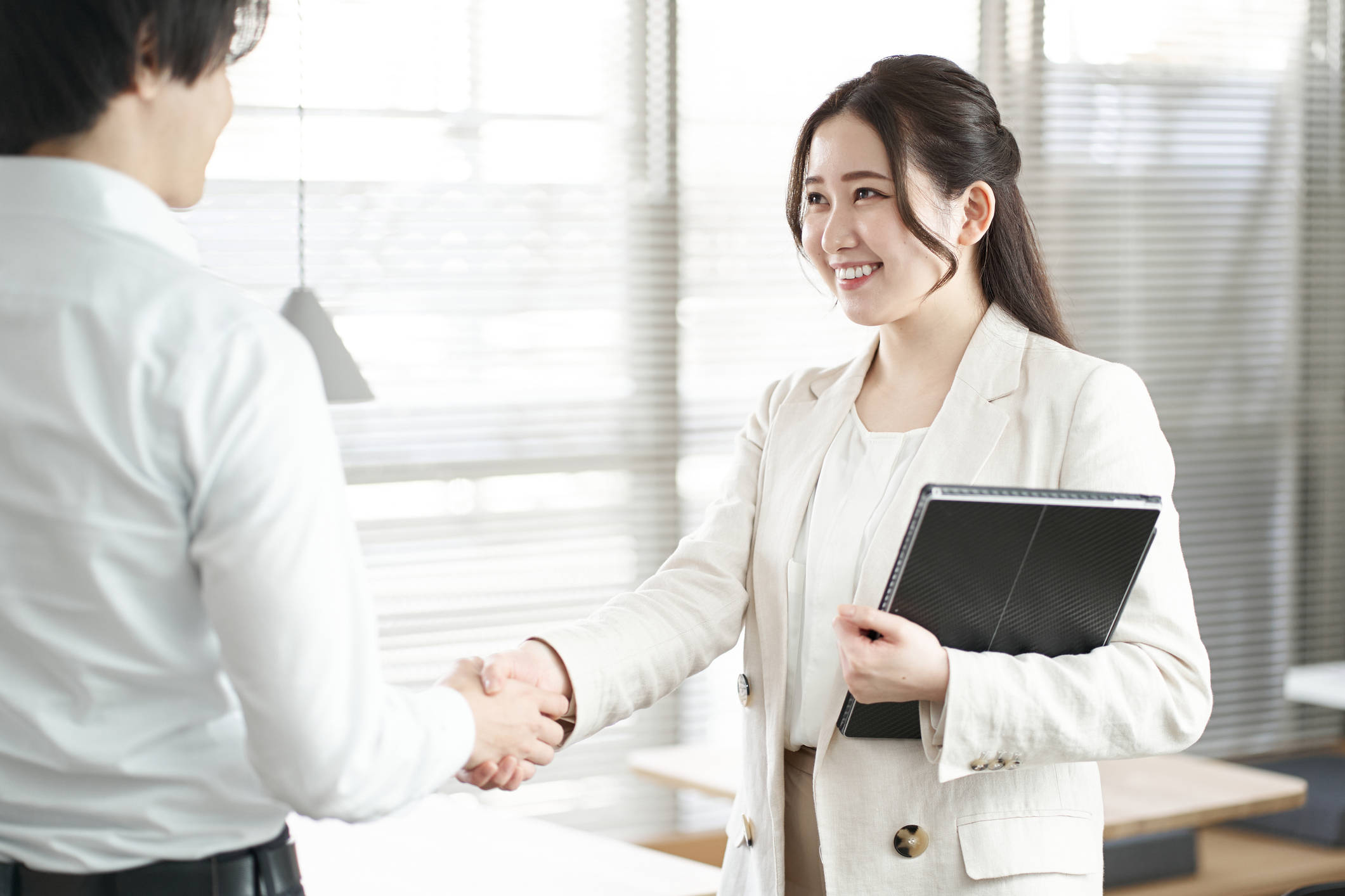 女性が笑顔で握手している画像