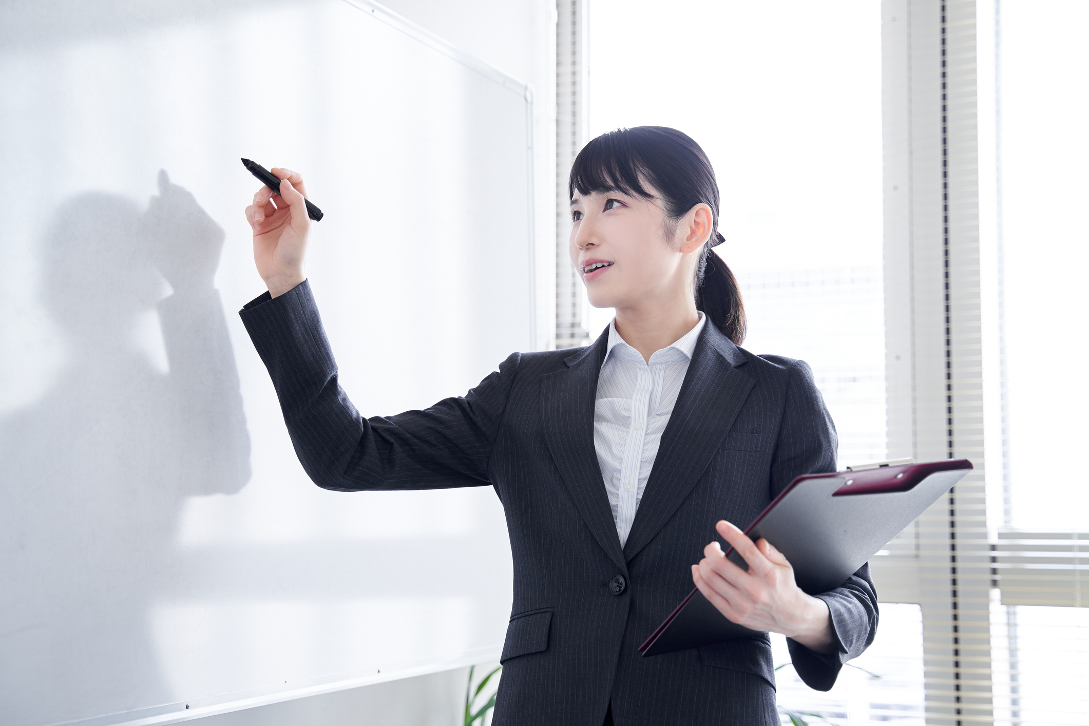 女性がホワイトボードに板書している画像